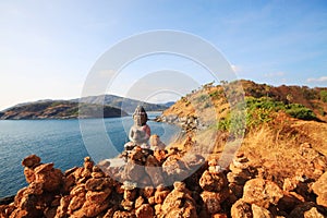 Beautiful Pyramid shape of stones arranged with Buddha statue in zen on rock mountain in seascape of sunset and sea horizon with