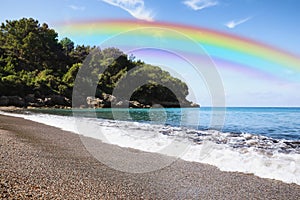 Beautiful rainbow in blue sky over beach and sea on sunny day