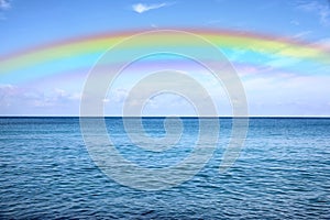 Beautiful rainbow in blue sky over sea on sunny day