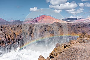 Beautiful rainbow caused by the crashing of the Ocean waves against the volcanic cliffs of Los Hervideros, Lanzarote