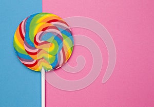 Beautiful rainbow lollipop on a blue and pink background