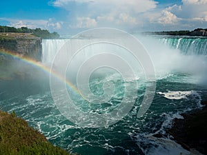 Beautiful rainbow on sunny day over Niagara Falls pool with Horseshow Falls in background