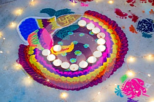 Beautiful rangoli made from colored powders and decorated with wax candle diyas on diwali eve