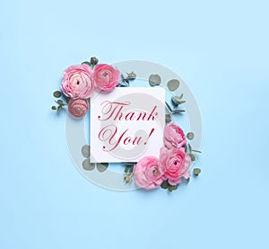 Beautiful ranunculus flowers and greeting card with text Thank You on light blue background, flat lay
