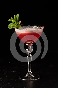 Beautiful red alcoholic cocktail with milk foam and coffee beans, decorated with mint leaves in a transparent glass