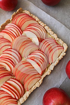 Beautiful red apple lattice tart, on a white baking sheet and light grey background with fresh ripe red apples asi