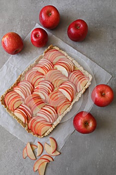 Beautiful red apple lattice tart, on a white baking sheet and light grey background with fresh ripe red apples asi