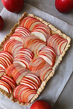 Beautiful red apple lattice tart, on a white baking sheet and light grey background with fresh ripe red apples asi