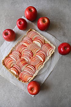 Beautiful red apple lattice tart, on a white baking sheet and light grey background with fresh ripe red apples asi