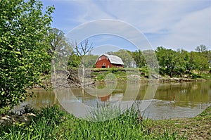 Beautiful red barn on the eroding banks of a river