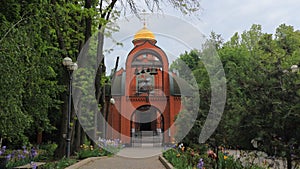 A beautiful red brick church with a golden dome and a bell tower under the arch