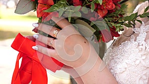 Beautiful red bridal bouquet in hands of young bride dressed in white wedding dress. slow motion. young girl in a