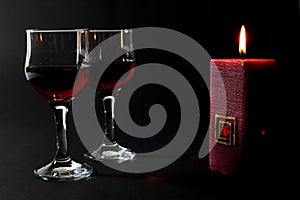 Beautiful Red Candle and Two Glass Cups of Red Wine Isolated on Black