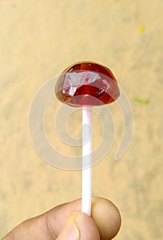 A beautiful red coloured jelly like choclate lolipop with white small pipe with bluured background