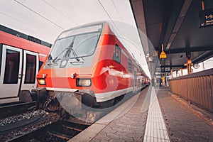 Beautiful red commuter train at railroad platform in the evening