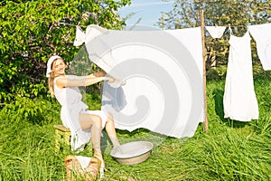 beautiful red girl in nightie hanging laundry outdoors. village woman working in countryside.