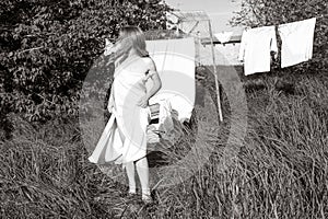 beautiful red girl in nightie hanging laundry outdoors. village woman working in countryside.