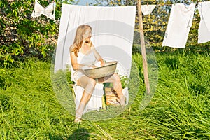 beautiful red girl in nightie hanging laundry outdoors. village woman working in countryside.