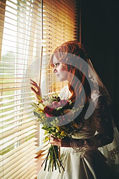 Beautiful red hair bride near window