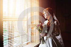 Beautiful red hair bride near window