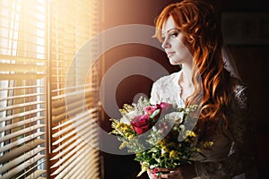 Beautiful red hair bride near window
