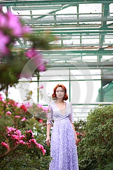 Red-haired girl in arranger where azalea blooms in a colorful flying dress photo