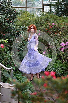 Red-haired girl in arranger where azalea blooms in a colorful flying dress photo