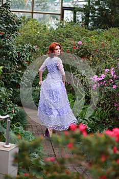 Red-haired girl in arranger where azalea blooms in a colorful flying dress photo