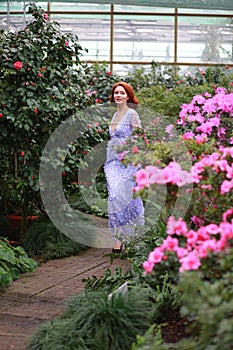 Red-haired girl in arranger where azalea blooms in a colorful flying dress photo