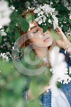 Beautiful red-haired girl posing and dreaming in the colors of an apple in the spring
