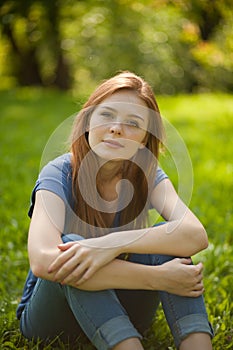 Beautiful red-haired girl sitting on grass