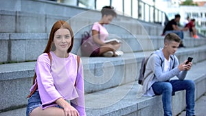 Beautiful red-haired teenager sitting stairs smiling camera, student exchange