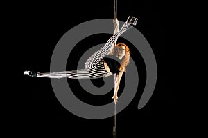 Beautiful and red haired woman performing pole dance