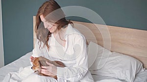 A beautiful red-haired woman sleeps in bed with her chihuahua dog.