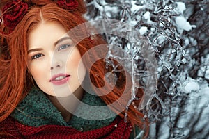 Beautiful red-haired young woman with perfect skin and make up posing on snowy and icy background