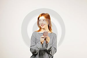 Beautiful red headed young woman posing, showing emotional facial expressions and making funny faces with mobile phone