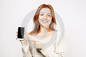 Beautiful red headed young woman posing, showing emotional facial expressions and making funny faces with mobile phone