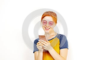 Beautiful red headed young woman posing, showing emotional facial expressions and making funny faces with mobile phone