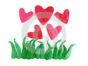 Beautiful red heart flowers, green grasses, plasticine clay dough