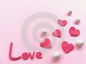 Beautiful red heart and love word plasticine, colorful clay dough, pink background