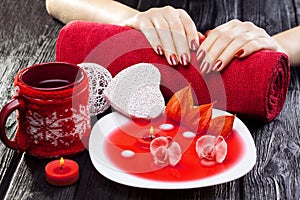 Beautiful red manicure with red orchid flower and towel on the black wooden table.