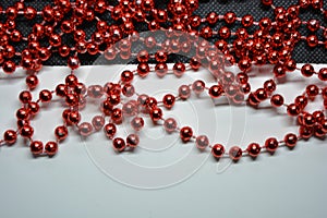 Beautiful red minor christmas beads for decorating Christmas tree arranged on white, black background.