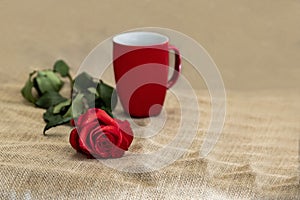Beautiful red rose and mug on rustic background with copy space