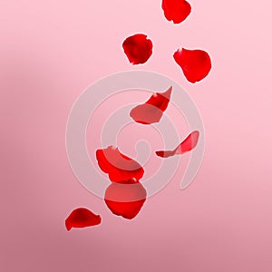 Beautiful red rose petals falling on light pink background