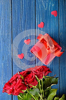 Beautiful red roses and gift box on wooden background