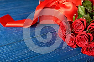 Beautiful red roses and gift box on wooden background