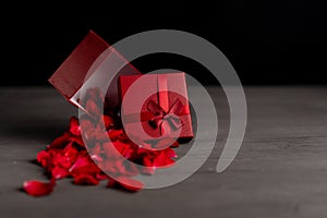 Beautiful red roses next to a gift red box on a dark cement background