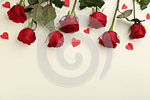Beautiful red roses and paper hearts on light background, flat lay with space for text. Valentine`s Day celebration