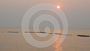 Beautiful red sunset on the sea red white buoys. The rays of red sun on the sea surface