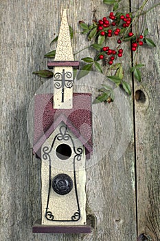 Beautiful red and white church birdhouse on rustic fence